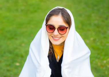 Yeşil arka planda gözlüklü bir ceket giyen genç bayan.