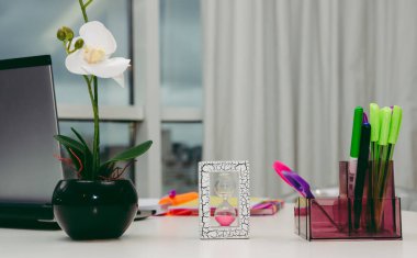 Çalışma masasında kum saati, çiçek ve kalemlerle çalışma masası.