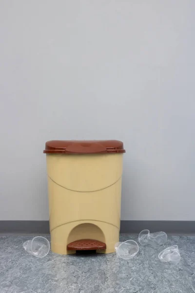 Trash. Garbage thrown out of the trash. Trash can with garbage next to it. Garbage can and plastic cups thrown down next to him.