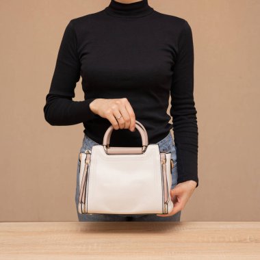 Bir kız bir çanta kadar işlevseldir. Kız beyaz çantayı sunar.