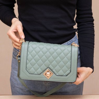 Bir kız bir çanta kadar işlevseldir. Kız yeşil çantayı sunar.