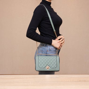 Bir kız bir çanta kadar işlevseldir. Kız yeşil çantayı sunar.