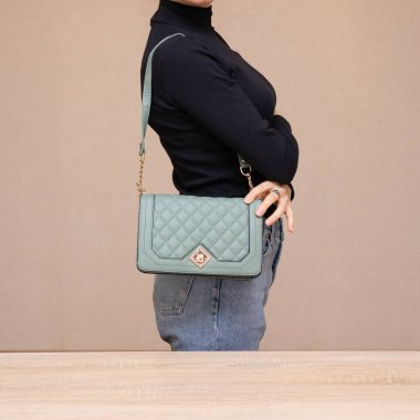 Bir kız bir çanta kadar işlevseldir. Kız yeşil çantayı sunar.