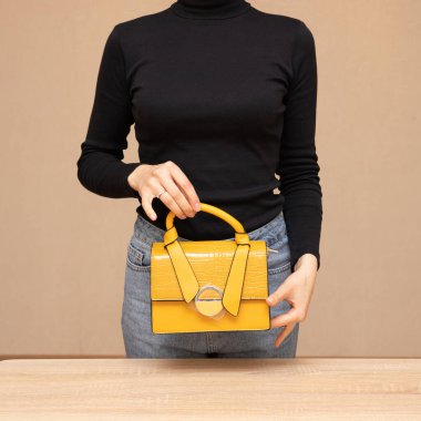 Bir kız bir çanta kadar işlevseldir. Kız sarı çantayı sunar.