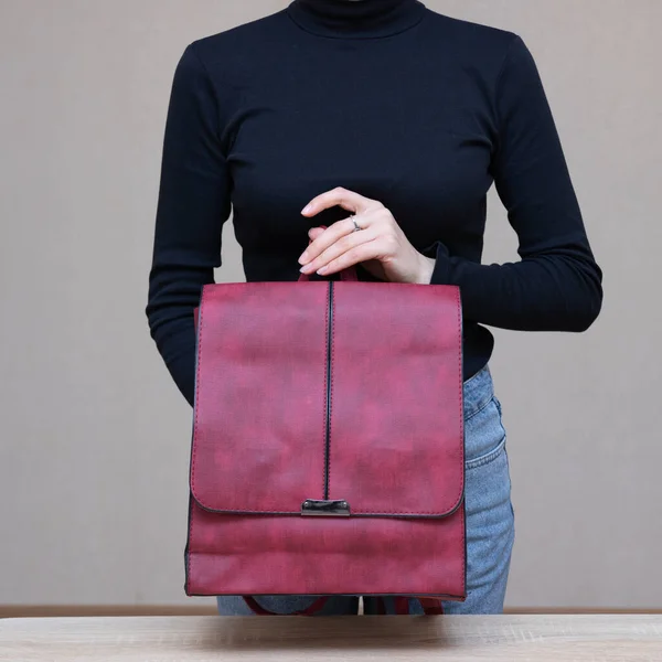 Bir kız bir çanta kadar işlevseldir. Kız kırmızı çantayı sunar.