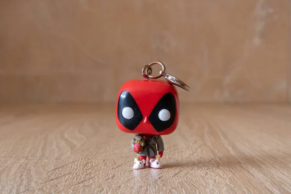 Tahta masada ölüm bilardosu minyatürü. Elinde oyuncak ayıyla Deadpool oyuncağı