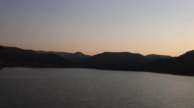 Su ve dağların üzerinde gün batımı