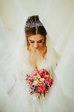 Elinde buket olan bir gelinlikle. Beyaz arkaplanda buketi olan gelin