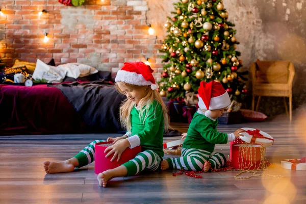 Duas Crianças Pijama Chapéus Natal Desembalar Presentes Natal Sala — Fotografia de Stock