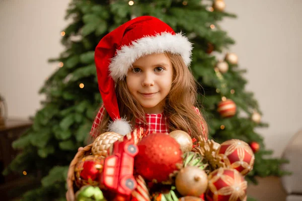 Menina Bonito Chapéu Santa Segurando Uma Cesta Brinquedos Contra Fundo — Fotografia de Stock