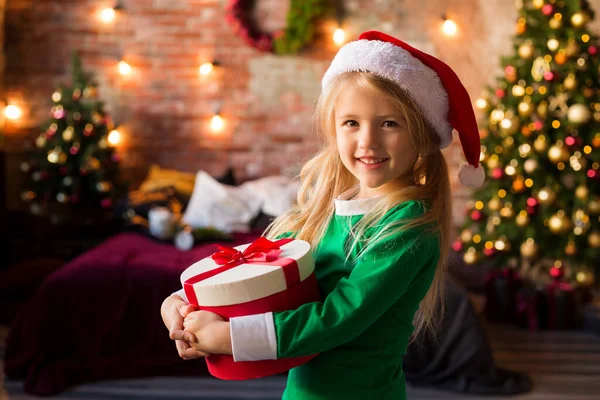 一个穿着睡衣 头戴礼品盒的可爱小女孩来到圣诞树旁 — 图库照片