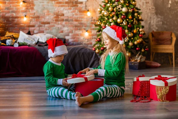 Dos Niños Pequeños Pijama Sombreros Navidad Desempaquetan Regalos Navidad Habitación —  Fotos de Stock