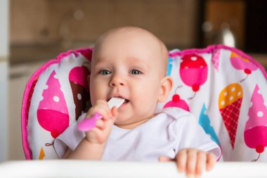 Sevimli küçük bebek renkli bebek koltuğunda yemek yiyor.