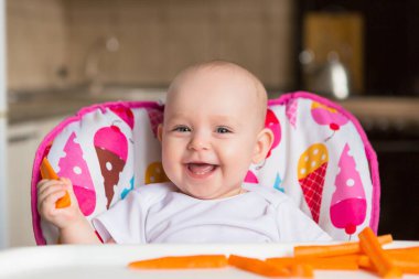 Sevimli küçük bebek renkli bebek koltuğunda yemek yiyor.