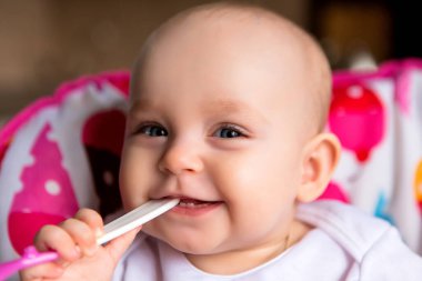 Sevimli küçük bebek renkli bebek koltuğunda yemek yiyor.