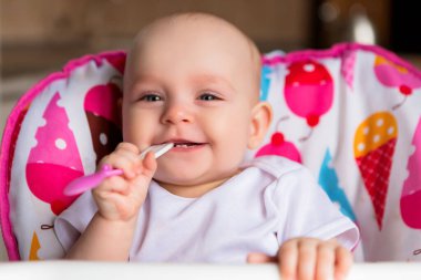 Sevimli küçük bebek renkli bebek koltuğunda yemek yiyor.