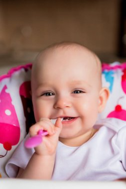 Sevimli küçük bebek renkli bebek koltuğunda yemek yiyor.