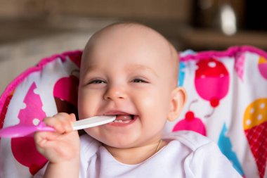 Sevimli küçük bebek renkli bebek koltuğunda yemek yiyor.