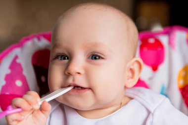 Sevimli küçük bebek renkli bebek koltuğunda yemek yiyor.