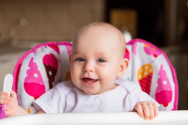 Sevimli küçük bebek renkli bebek koltuğunda yemek yiyor.