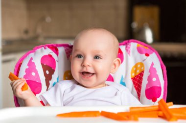 Sevimli küçük bebek renkli bebek koltuğunda yemek yiyor.