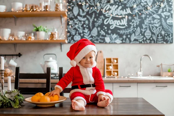 圣诞老人宝宝坐在厨房里 在一块用俄语写着 新年快乐 的图形板上写着 — 图库照片