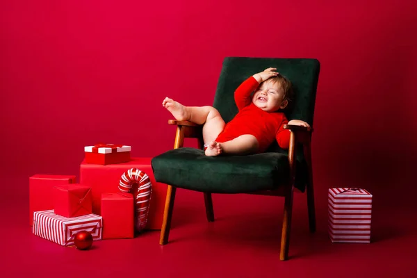 Söt Baby Santa Sitter Stol Bland Julklappar Röd Bakgrund Julkoncept — Stockfoto