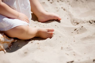 Küçük çocuk ayakları parlak güneş ışığında kumların üzerinde