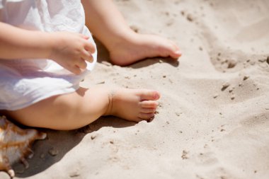 Küçük çocuk ayakları parlak güneş ışığında kumların üzerinde