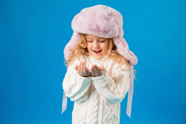 Κοριτσάκι Χειμωνιάτικα Ρούχα Κοιτάζει Χέρια Της Στο Φόντο Του Μπλε — Φωτογραφία Αρχείου