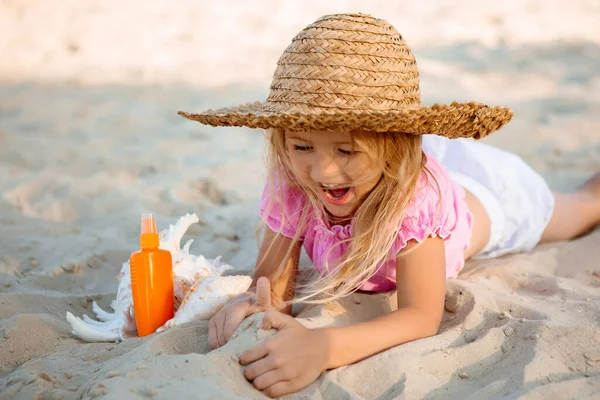 Смеющаяся Маленькая Девочка Соломенной Шляпе Позирующая Песке Раковиной Спрей Бутылкой — стоковое фото