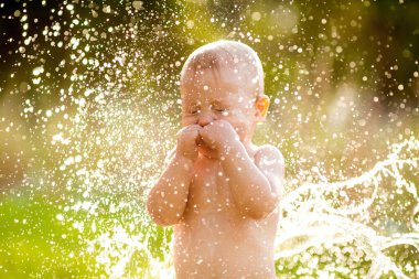 Suyla çevrili küçük bir çocuk. Güneşin arkasına sıçrıyor.