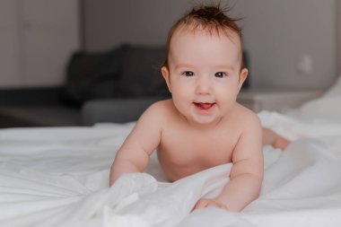 Sevimli küçük erkek bebek yatakta yatıyor.