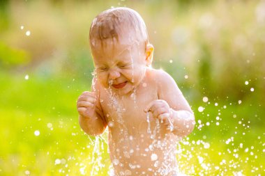 Suyla çevrili küçük bir çocuk. Güneşin arkasına sıçrıyor.