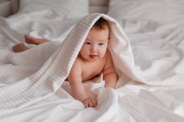 Bebek çocuk kafasında havluyla yatakta yatıyor.