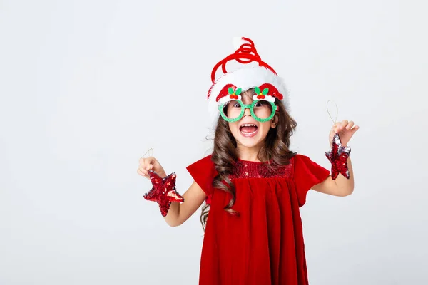 Noel şapkalı ve gözlüklü küçük bir kız Noel süslemeleri taşıyor.