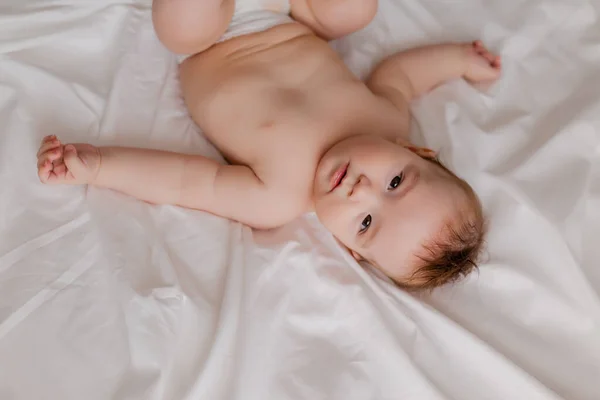 男婴躺在脚向上的白色床单上 — 图库照片