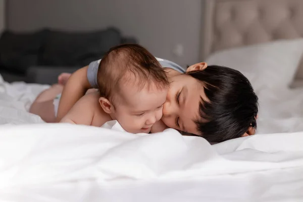 Dois Irmãos Abraçando Lençóis Brancos Cama — Fotografia de Stock