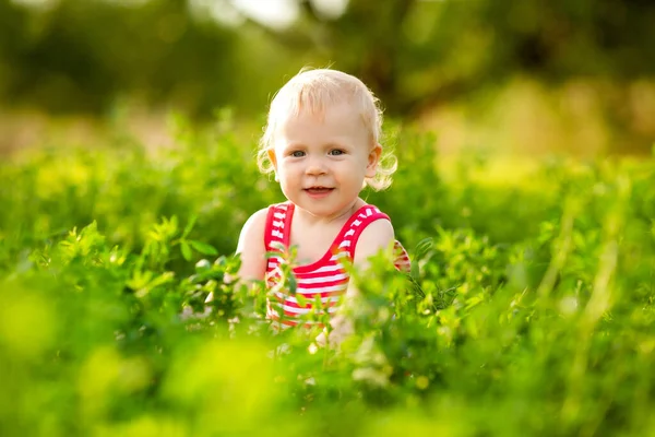 笑着蹒跚学步的小女孩站在茂密的绿色灌木丛中 — 图库照片