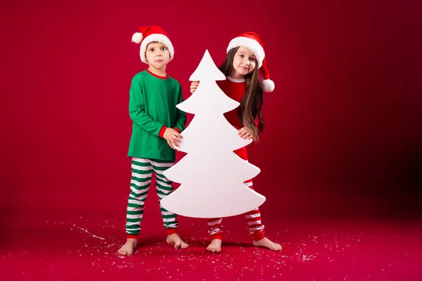 身穿节日服装 手持圣诞树形装饰品的兄妹 — 图库照片
