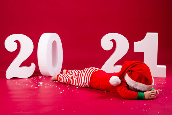 мальчик лежит на полу студии в костюме Санты с 2021 номерами