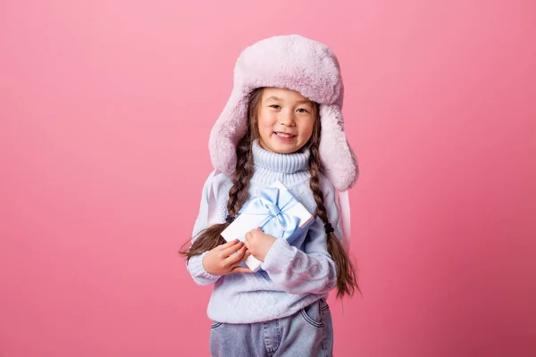 Kış Şapkalı Küçük Asyalı Kız Pembe Arka Planda Hediye Kutusuyla — Stok fotoğraf