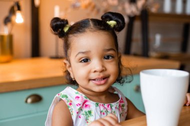 Küçük tatlı Afrikalı Amerikalı kız evde, mutfakta.