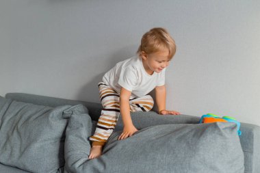 Evdeki kanepede oynayan sevimli bir çocuğun portresi. 