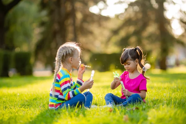 Duas Meninas Sentam Gramado Verão Sopram Bolhas Sabão Crianças Etnia — Fotografia de Stock