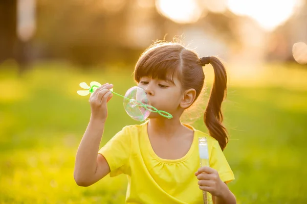 可爱的印度小女孩在夏天的草坪上吹肥皂泡 — 图库照片