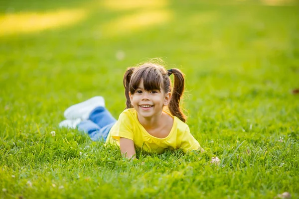 穿着黄色T恤的快乐的印度小女孩在夏天的草坪上笑着 — 图库照片