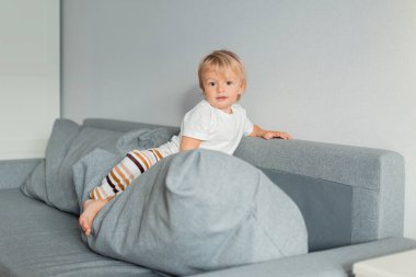 Evdeki kanepede oynayan sevimli bir çocuğun portresi. 