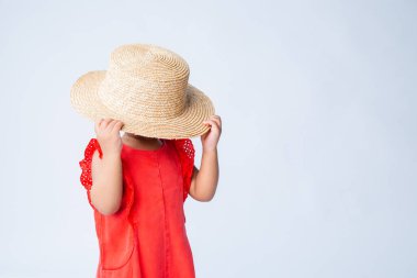 Kırmızı yaz kıyafetleri ve beyaz arka planda hasır şapkası olan küçük Afrikalı Amerikalı kız.