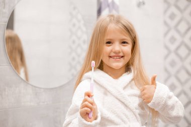 Banyoda dişlerini yıkayan bornozlu tatlı bir kız. 